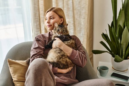 Eine kurzhaarige Frau sitzt auf einer Couch und hält friedlich ihre Katze in einem gemütlichen Innenraum.