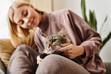 Photo for A woman with short hair sits on a couch, lovingly petting her cat. - Royalty Free Image