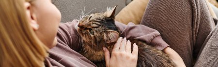Photo for A woman with short hair sits on a sofa, gently petting a contented cat in a cozy domestic setting. - Royalty Free Image