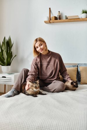 A woman with short hair serenely sitting on a bed, gently petting a calico cat beside her.