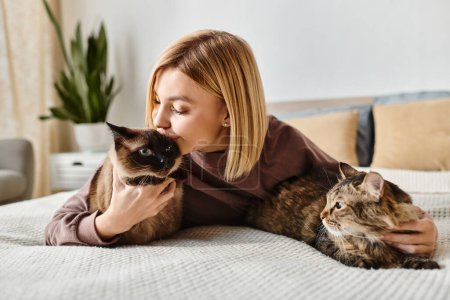Une femme aux cheveux courts se couche paisiblement sur un lit, tenant un chat content dans ses bras.