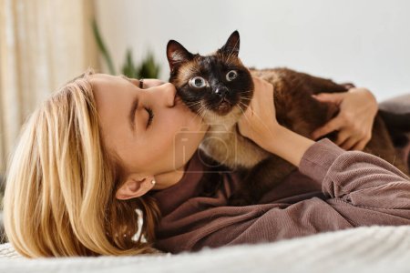 A woman with short hair lying on a bed, tenderly kissing her cat in a peaceful moment of bonding and affection.