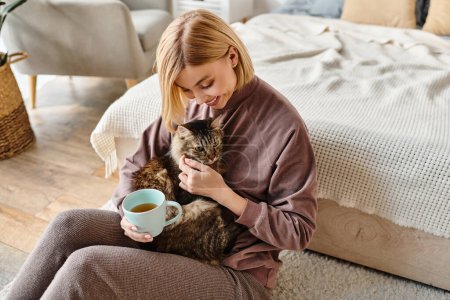 A serene woman with short hair sitting on the floor, affectionately holding her cat at home.