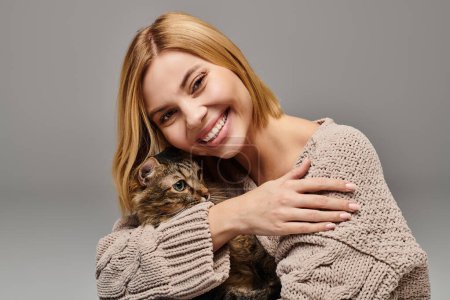 Téléchargez les photos : Une femme aux cheveux courts berçant un chat dans ses bras, partageant un moment paisible à la maison. - en image libre de droit
