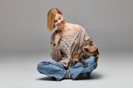 Eine Frau sitzt auf dem Boden und umarmt ihre Katze in einem ruhigen Moment zu Hause liebevoll.