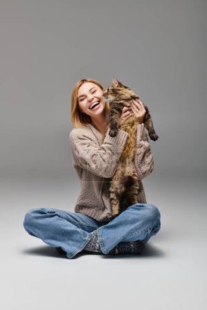 Photo for A woman with short hair sits peacefully on the floor, tenderly holding her cherished cat in her arms. - Royalty Free Image