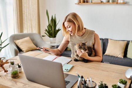 A stylish woman with short hair works on her laptop at a table as her furry feline companion sits beside her.