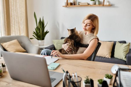 Foto de Una mujer con el pelo corto se sienta en una mesa, suavemente sosteniendo a un gato en su regazo, ambos en un momento tranquilo en casa. - Imagen libre de derechos