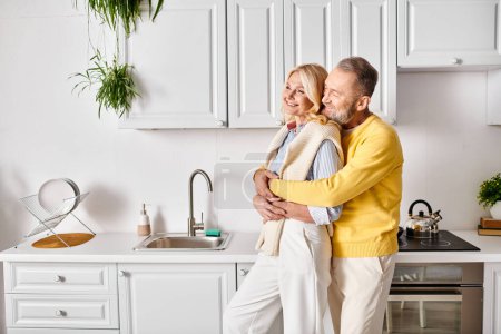 A mature man and woman in cozy homewear sharing a loving hug in a cozy kitchen setting.