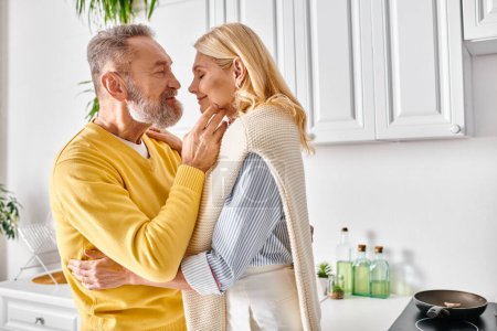 A mature loving couple embraces in their cozy kitchen, sharing a tender moment together.