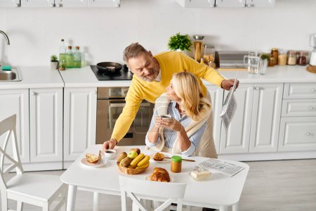 Ein reifer Mann und seine Frau posieren zusammen in einer gemütlichen Küche und teilen einen liebevollen und herzlichen Moment.