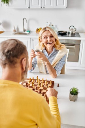 A mature, loving couple in cozy homewear engage in a challenging game of chess in their kitchen, focused and thoughtful.