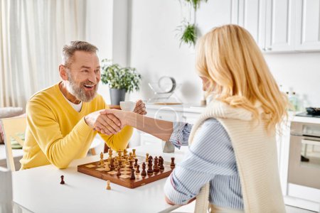 A mature man and woman engaged in a strategic game of chess in their cozy kitchen, enjoying a moment of intellectual challenge and connection.