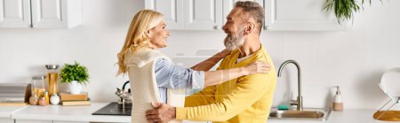 Photo for A mature man hugging woman in a loving embrace in their cozy kitchen at home. - Royalty Free Image