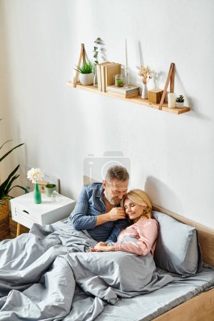 A mature man and woman in cozy homewear, laying together on a bed, sharing a moment of intimacy and comfort.