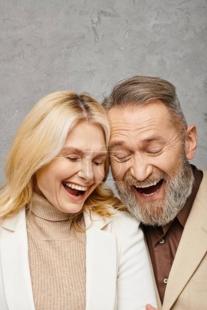 Ein reifer Mann und eine reife Frau, beide elegant gekleidet, teilen einen Moment der Freude, als sie zusammen lachen.