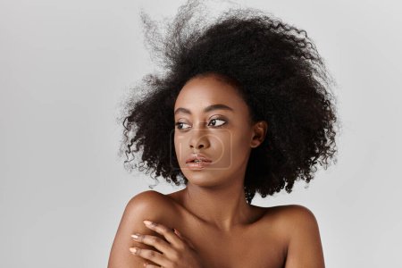 A captivating young African American woman with curly hair is gazing away from the camera.