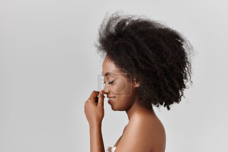 Téléchargez les photos : Une jeune afro-américaine aux cheveux bouclés pose en toute confiance pour une photo en studio, mettant en valeur sa magnifique afro. - en image libre de droit