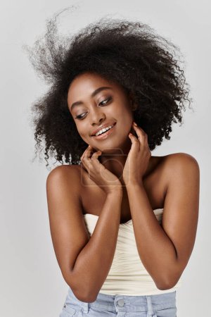 Una hermosa joven afroamericana posa graciosamente con su pelo rizado ondeando en el viento.