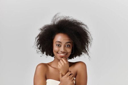 Eine schöne junge Afroamerikanerin mit lockigem Haar posiert selbstbewusst in einem Studio für ein Foto.