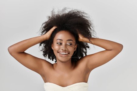 Téléchargez les photos : Femme afro-américaine aux cheveux bouclés, incarnant élégance et grâce dans un cadre de studio. - en image libre de droit