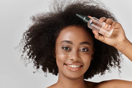 Eine schöne junge Afroamerikanerin mit lockigem Haar in einem Studio-Setting und demonstriert ein Haarpflegekonzept.
