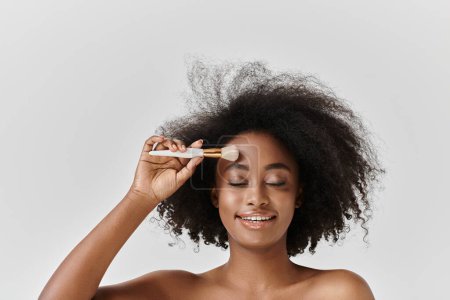 A beautiful young African American woman with curly hair in a studio, emphasizing skin care and self-care.
