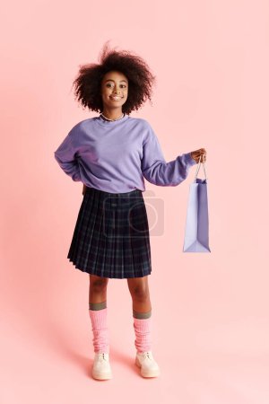 Young African American woman in purple sweater, plaid skirt, holding blue bag in a fashionable studio setting.