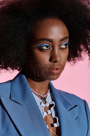 Photo for Stylish African American woman with curly hair confidently wearing a blue suit in a studio setting. - Royalty Free Image