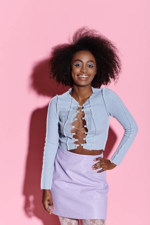 A stylish young African American woman with curly hair posing gracefully in a skirt in a studio setting.