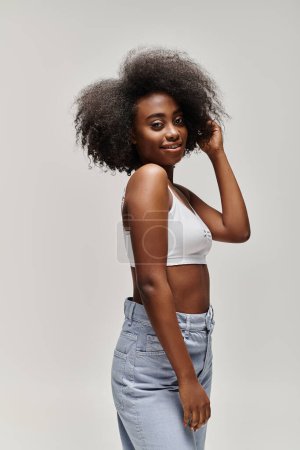 A young African American woman with a curly afro hair posing for a photograph in a studio setting.