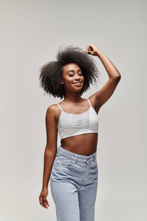 Foto de Una joven afroamericana impresionante con el pelo rizado, estilizado en un afro, posa con confianza para una cámara. - Imagen libre de derechos