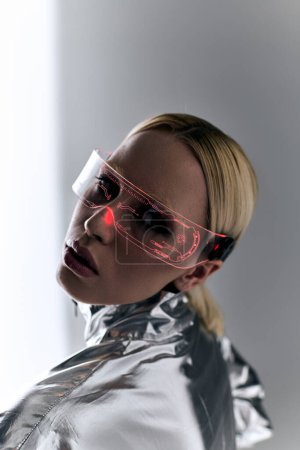 außergewöhnliche Frau mit Science-Fiction-Brille in Roboterkleidung blickt vor grauem Hintergrund in die Kamera