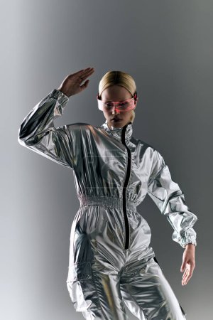 extraordinary woman with futuristic glasses in silver attire doing robotic motions and looking away