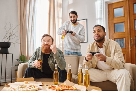 Three cheerful men, of different ethnicities, sit closely on a couch, playing video games together with joy and camaraderie.