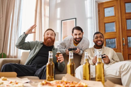 Three handsome, cheerful men of different races relax on a couch with beer and pizza, enjoying each others company.