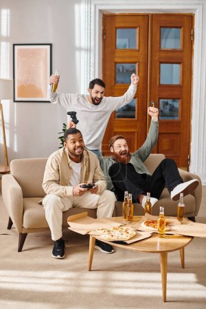 Tres hombres alegres y guapos de diferentes razas sentados encima de un sofá, disfrutando de un buen rato juntos en un entorno casual.