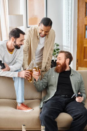 Tres hombres alegres e interraciales en atuendo casual, unidos y pasándolo bien juntos en un sofá en casa.