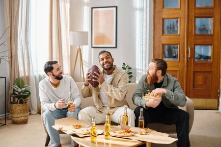 Three cheerful, interracial men in casual attire enjoying pizza together around a table in a cozy setting.