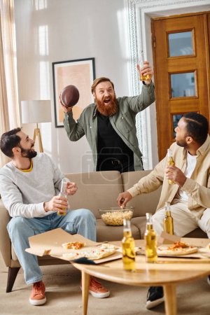 Drei fröhliche, gut aussehende Männer verschiedener Rassen in lässiger Kleidung, die sich auf einer Couch in Gesellschaft amüsieren.