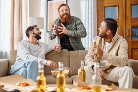 Foto de Tres hombres alegres y guapos de diferentes razas en atuendo casual, disfrutando de la compañía de los demás mientras están sentados en la parte superior de un sofá. - Imagen libre de derechos