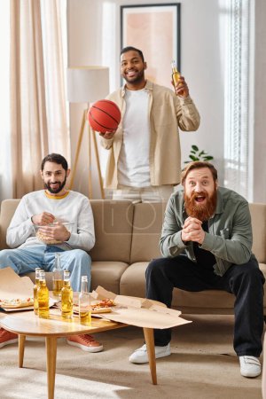Three handsome, cheerful men of different races, dressed casually, enjoy each others company in a living room setting.