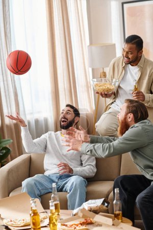 Three cheerful, interracial men in casual attire play a competitive game of basketball, showcasing friendship and teamwork.