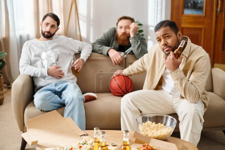 Ein Trio gut aussehender Männer unterschiedlicher Herkunft teilt Lachen und Bindung auf einer gemütlichen Couch in einem stilvollen Wohnzimmer.