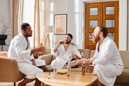 Three cheerful men of different backgrounds, in bathrobes, share laughter and camaraderie around a living room table.