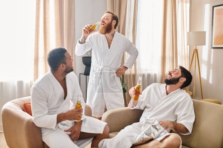 Tres hombres diversos y alegres en albornoces sentados encima de un sofá, disfrutando de la compañía de los demás y compartiendo risas.