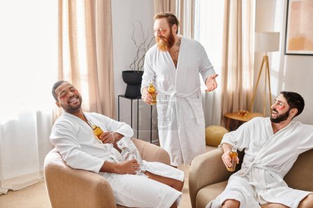 Three diverse, cheerful men in bathrobes, enjoying each others company while sitting together in a cozy living room.
