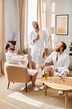 Tres hombres diversos y alegres en albornoces se sientan juntos en una sala de estar, compartiendo risas y creando recuerdos.