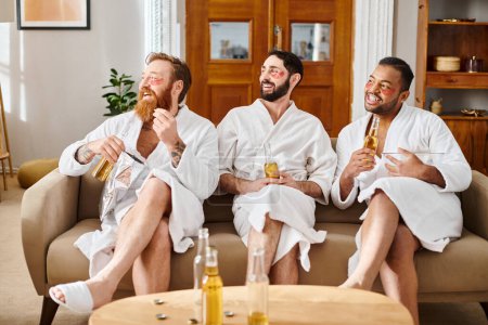 Photo for Three diverse, cheerful men wearing bathrobes are enjoying a great time together while sitting on top of a couch. - Royalty Free Image