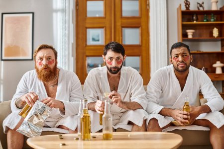 Photo for Three pensive, diverse men in bathrobes sit atop a couch, sharing good time and camaraderie. - Royalty Free Image